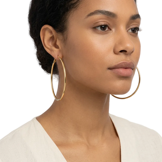 Duże złote kolczyki koła 70 mm na modelce na białym tle