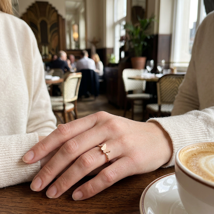 Jeden złoty pierścionek z małym motylem na dłoni przy kawie w restauracji
